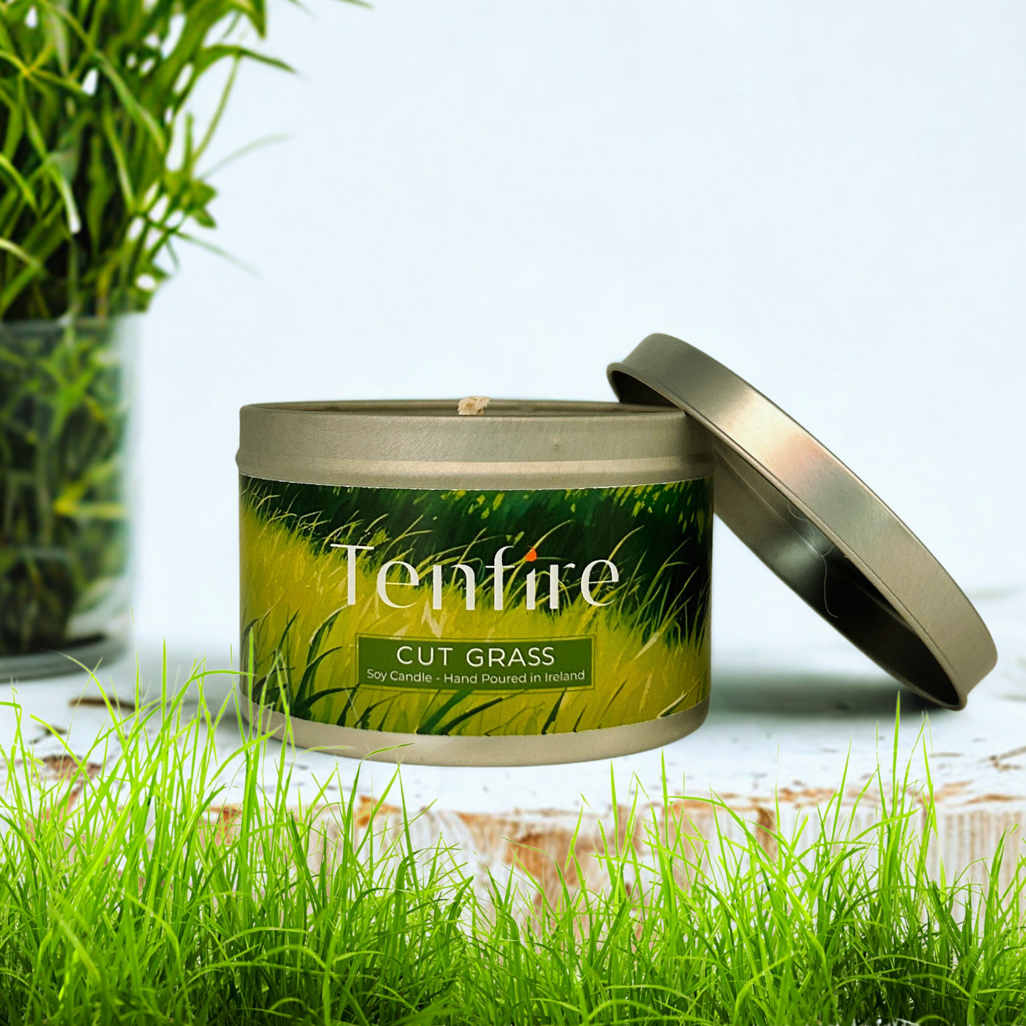 Open Cut Grass candle tin surrounded by grass