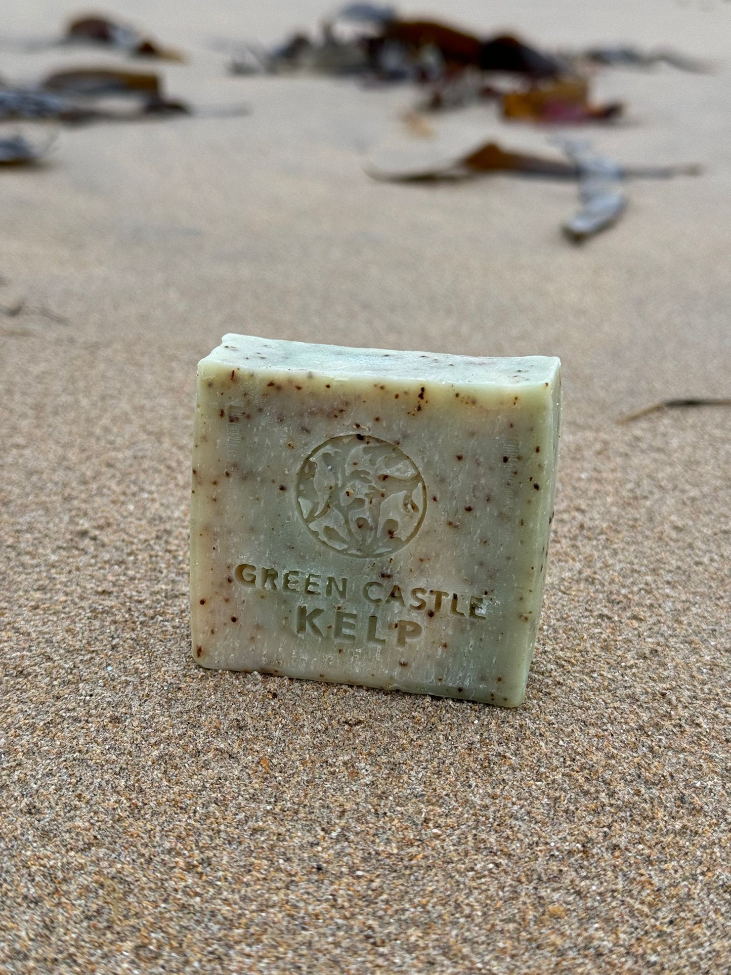 a speckled green and beige soap bar sitting on the sand