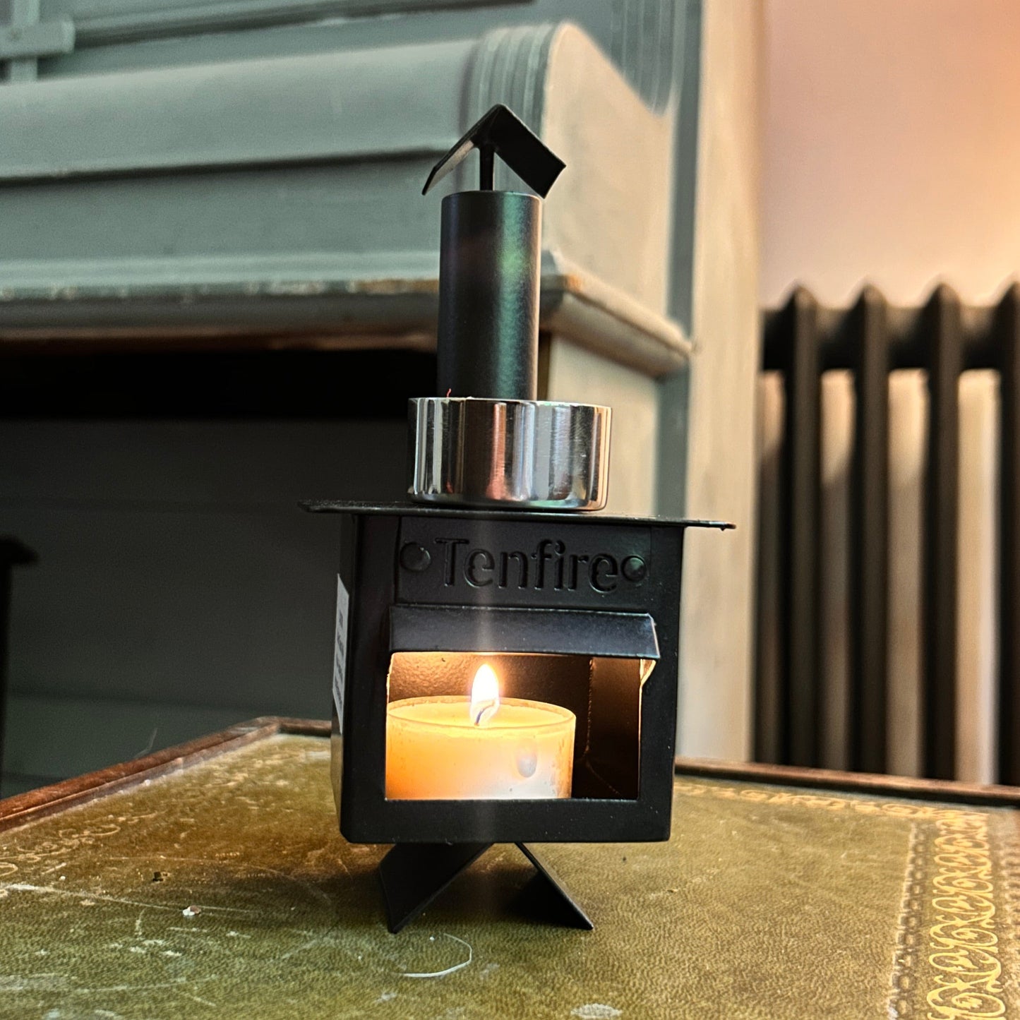 Mini burner with a lit candle inside on a wooden surface.
