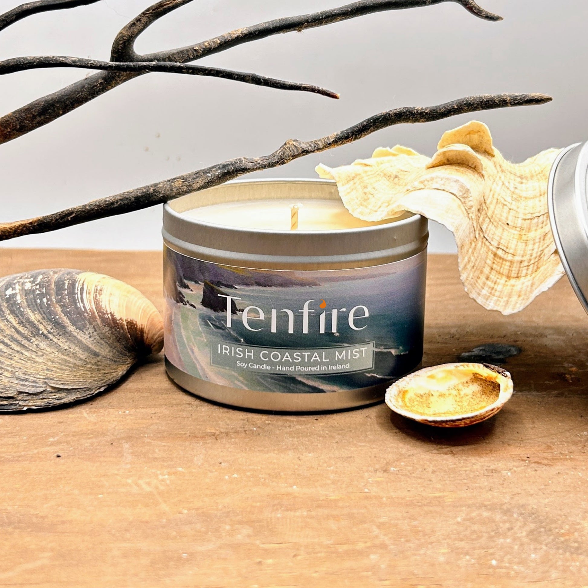 Tin candle labeled 'Tenfire Irish Coastal Mist' with decorative elements on a wooden surface.