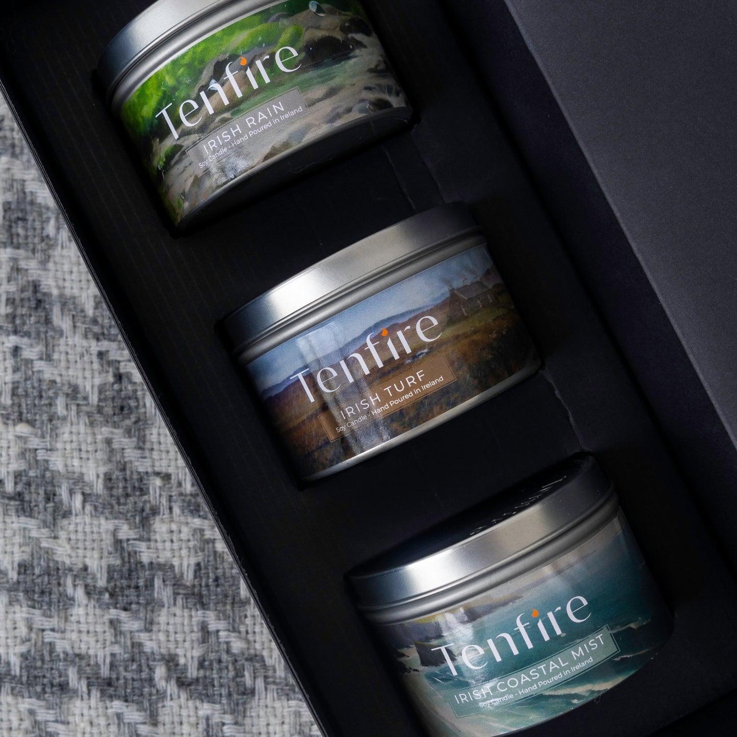 Three tins of Tenfire candles in a black box on a textured surface