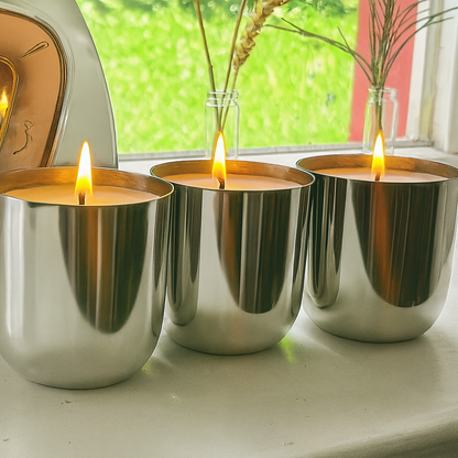three large smooth silver vessels with lit candles