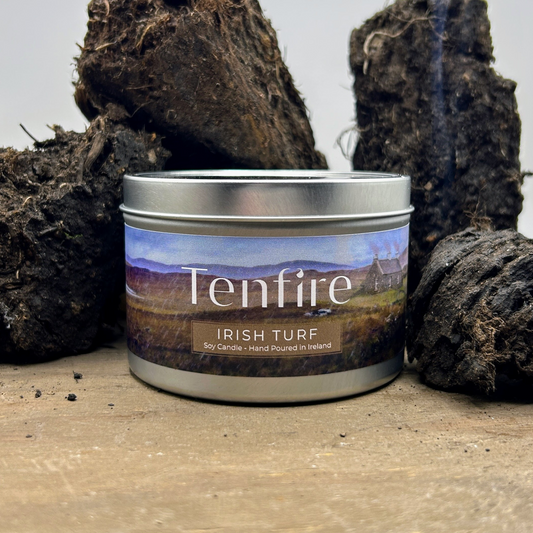 candle tin called irish turf surrounded by smoking turf and sitting on a wooden board