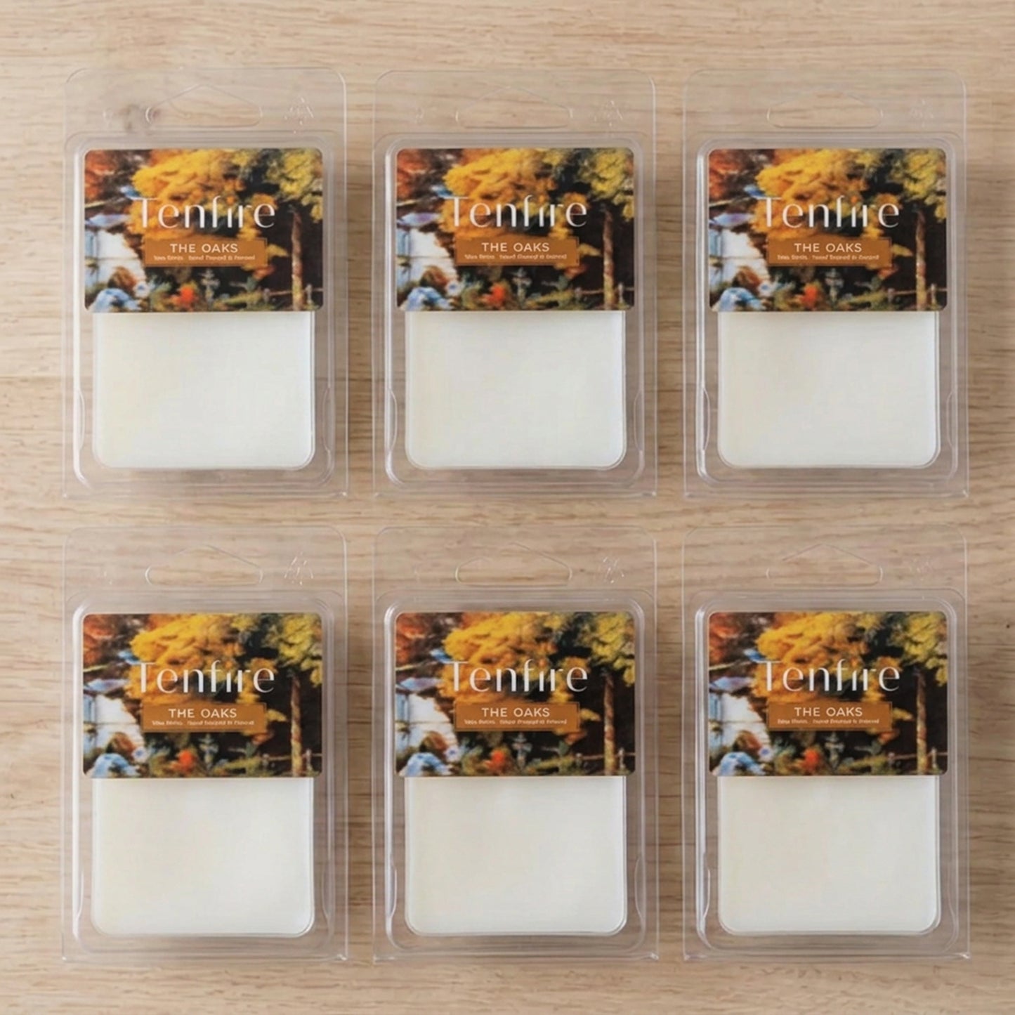 Six wax melts in clear clamshell packaging arranged in a 2x3 grid on a light wood surface. Each package has an autumn-themed label with the brand name 'Tenmire' and scent name 'The Oak'.