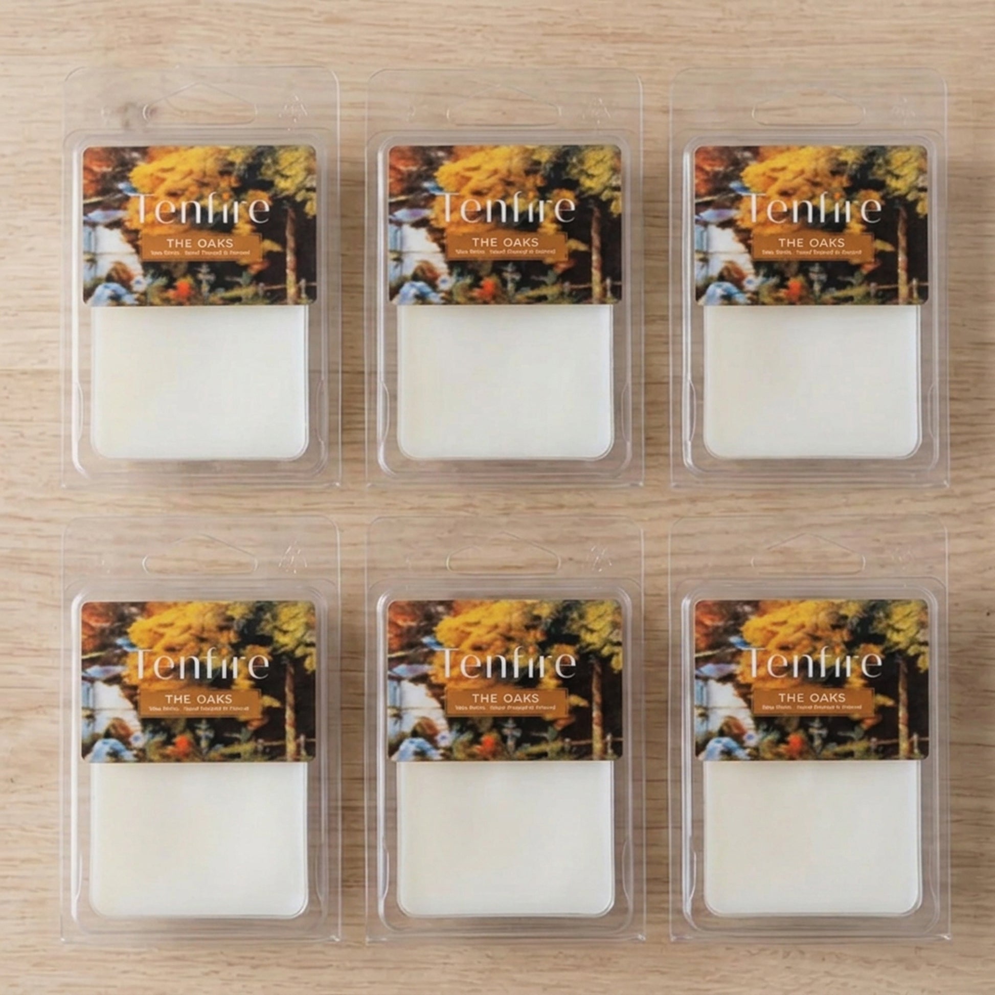 Six wax melts in clear clamshell packaging arranged in a 2x3 grid on a light wood surface. Each package has an autumn-themed label with the brand name 'Tenmire' and scent name 'The Oak'.