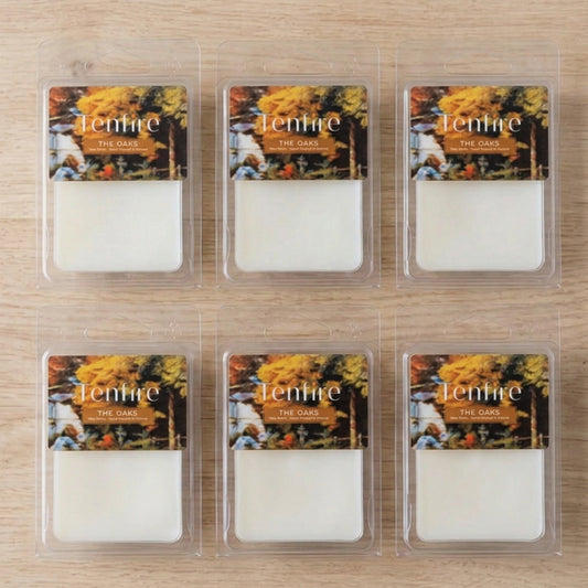 Six wax melts in clear clamshell packaging arranged in a 2x3 grid on a light wood surface. Each package has an autumn-themed label with the brand name 'Tenmire' and scent name 'The Oak'.