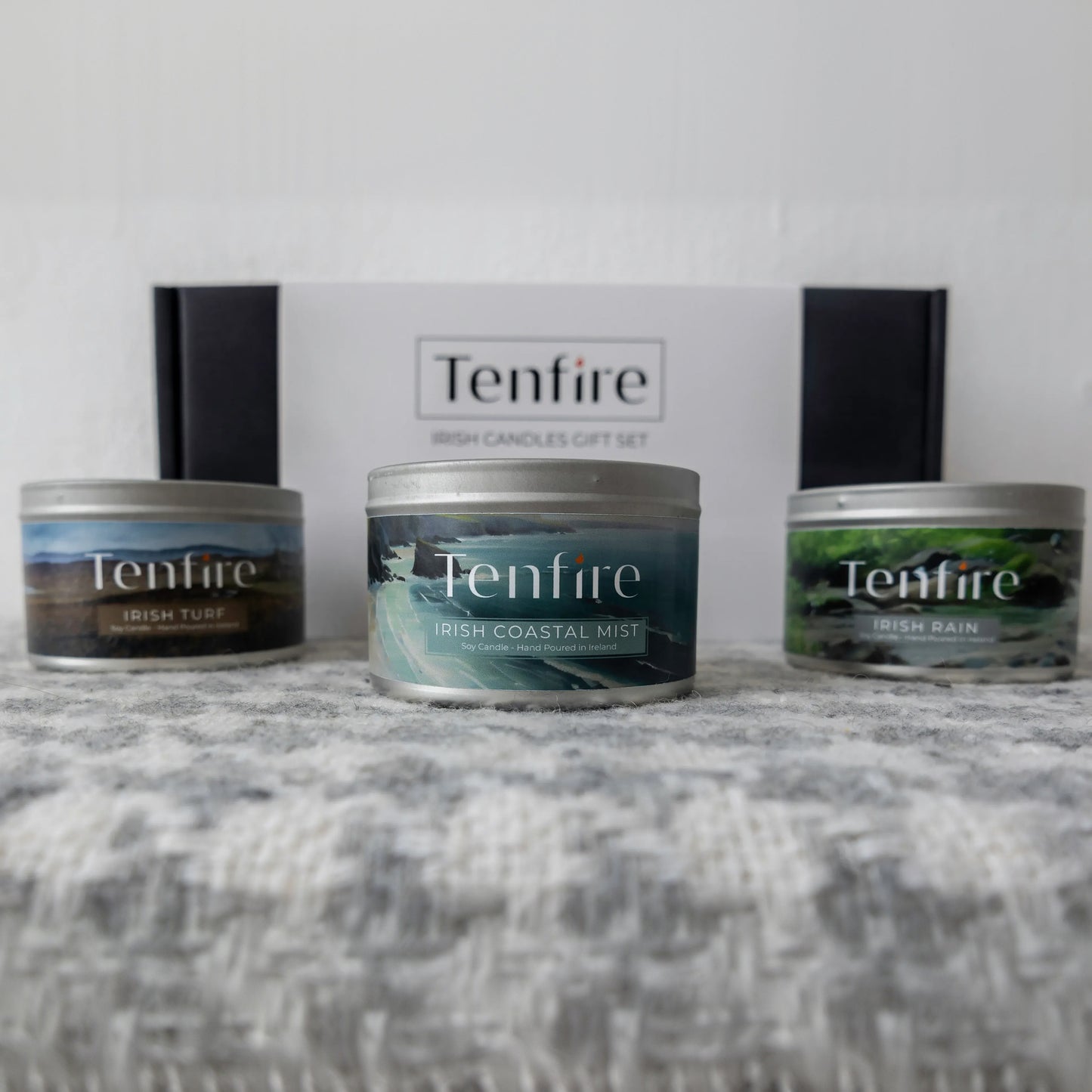 Three Tenfire candles on a textured surface with a branded box in the background.