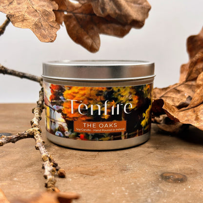 Tenfire candle labeled 'The Oaks' on a wooden surface with leaves and branches.