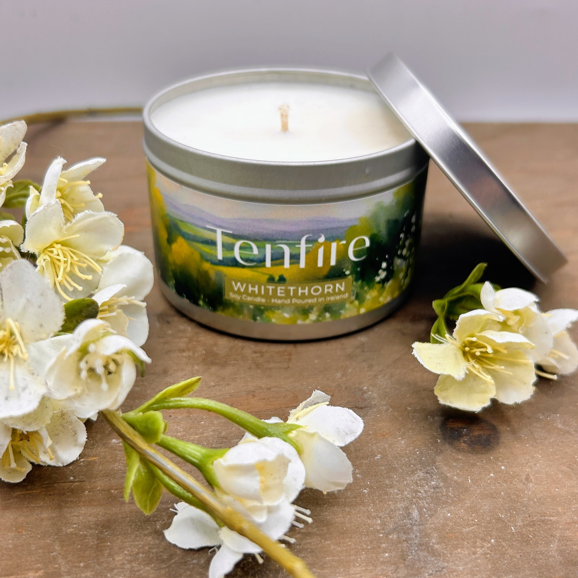 open candle tin called whitethorn sitting on a wood board surrounded by white flowers