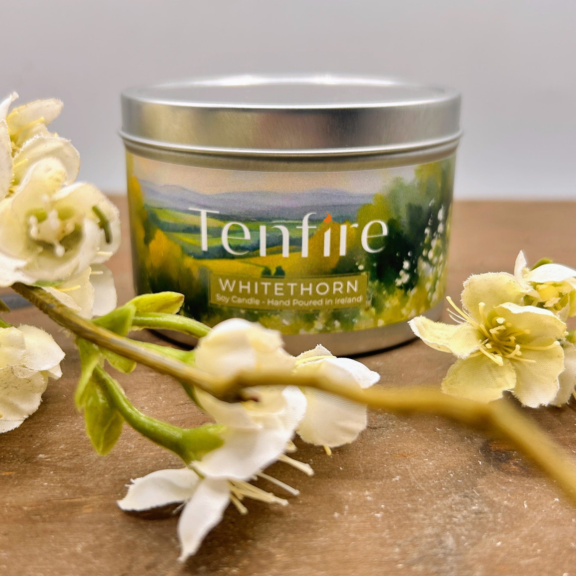 Tenfire Whitethorn candle with floral arrangement on a wooden surface