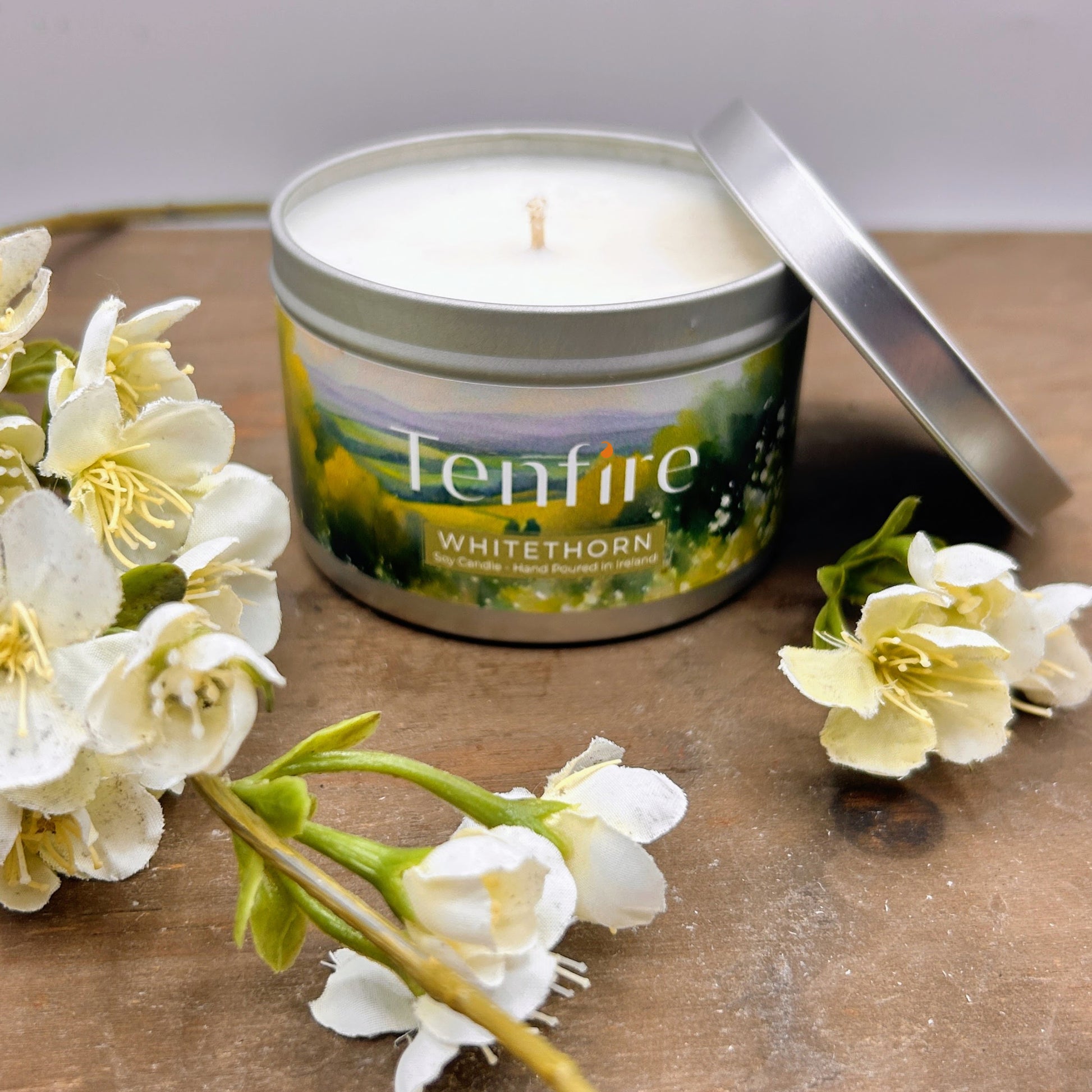 Tenfire White Thorn candle in a tin with flowers on a wooden surface